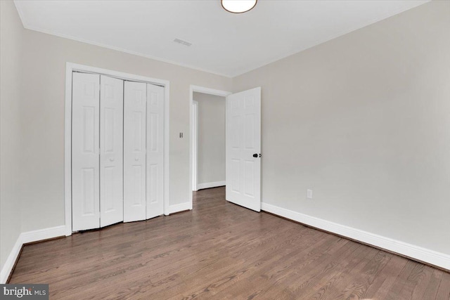 unfurnished bedroom featuring visible vents, baseboards, and wood finished floors