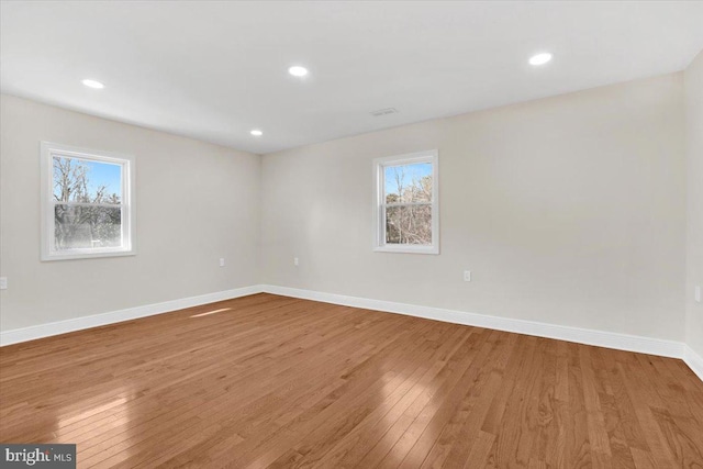 empty room featuring recessed lighting, baseboards, and hardwood / wood-style flooring