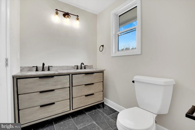 bathroom with baseboards, a sink, toilet, and double vanity