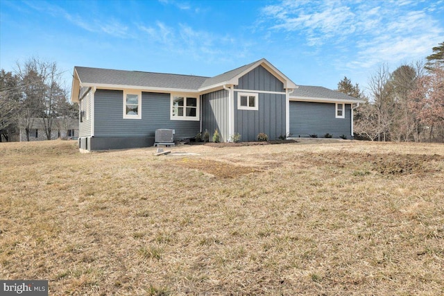 exterior space featuring central AC, board and batten siding, and a yard