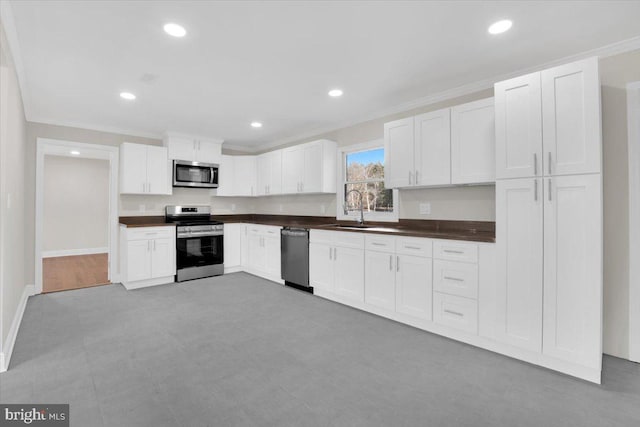 kitchen featuring dark countertops, white cabinets, stainless steel appliances, and crown molding