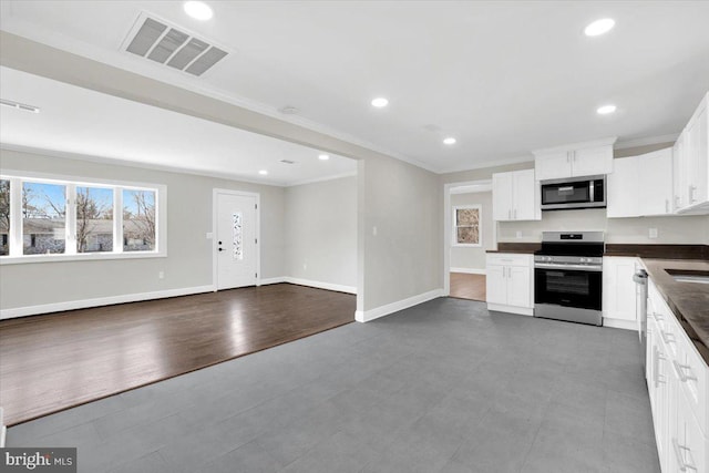 kitchen featuring crown molding, stainless steel appliances, dark countertops, visible vents, and open floor plan