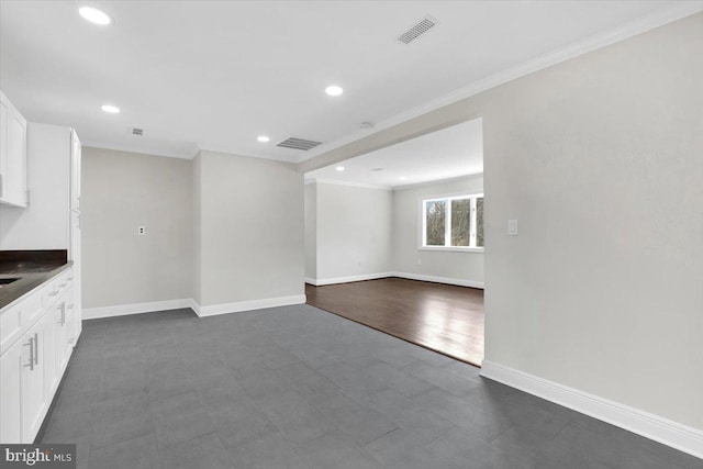 unfurnished living room with ornamental molding, visible vents, and baseboards