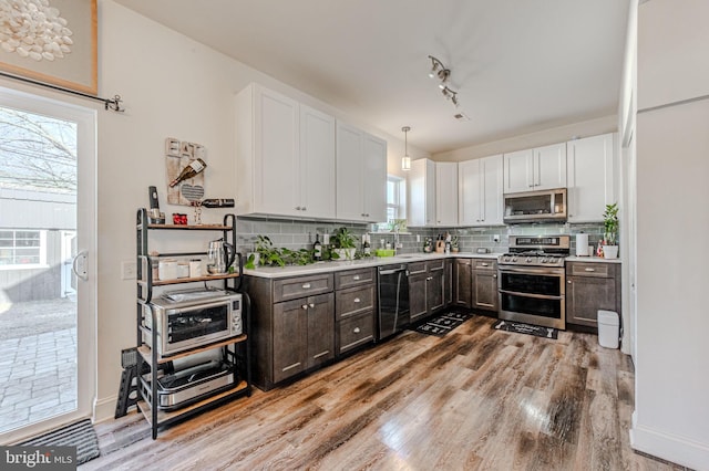 kitchen featuring stainless steel appliances, light countertops, light wood-style floors, and decorative backsplash