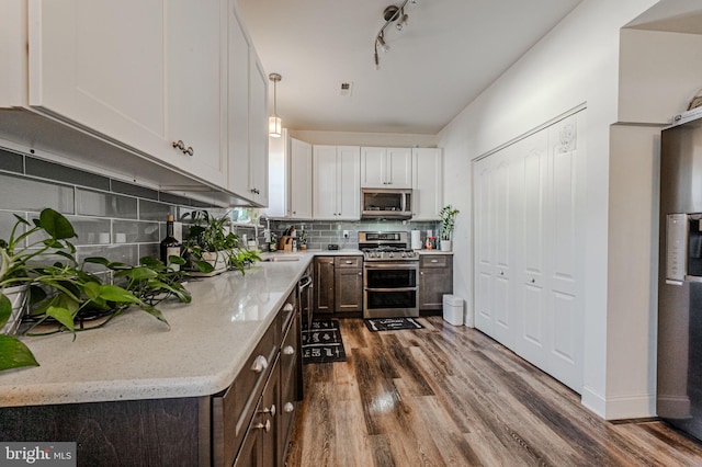 kitchen with dark brown cabinetry, tasteful backsplash, dark wood-style flooring, light stone countertops, and stainless steel appliances