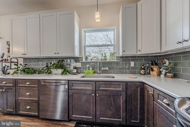 kitchen featuring light countertops, stainless steel dishwasher, a sink, and tasteful backsplash