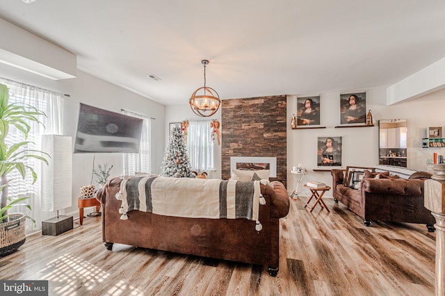 living area with a wealth of natural light, visible vents, an inviting chandelier, and wood finished floors