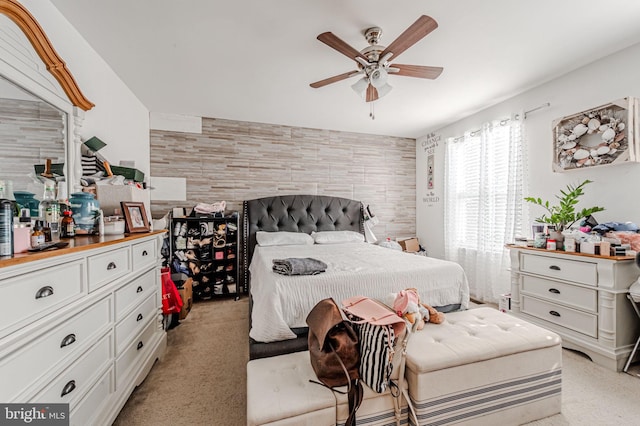 bedroom featuring an accent wall, light colored carpet, and ceiling fan