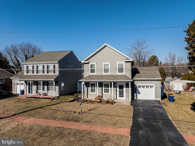 traditional home featuring aphalt driveway, covered porch, a garage, roof with shingles, and a front yard