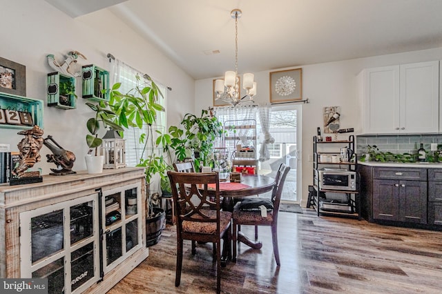 dining room with wood finished floors, visible vents, and an inviting chandelier