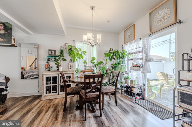 dining room featuring a chandelier, baseboards, and wood finished floors