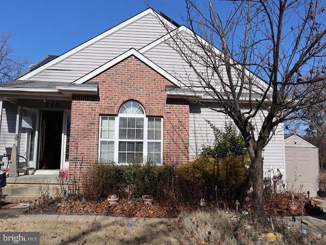 view of front facade with a shed and brick siding