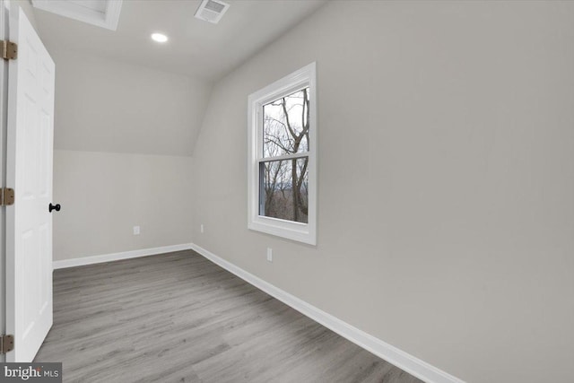 additional living space with visible vents, baseboards, wood finished floors, vaulted ceiling, and recessed lighting