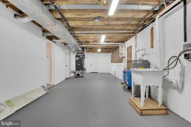 unfinished basement with concrete block wall, a sink, and heating unit