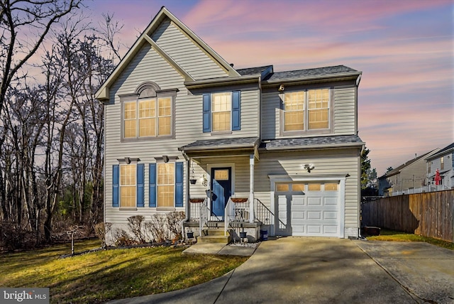 traditional-style home featuring a front lawn, driveway, fence, roof with shingles, and a garage