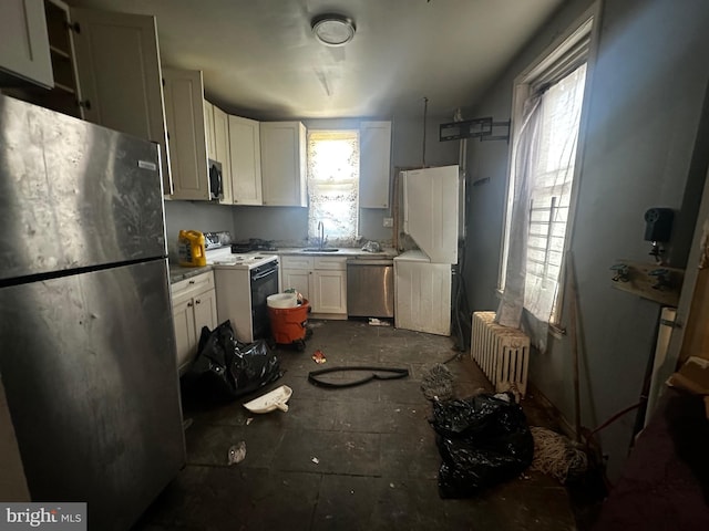 kitchen featuring stainless steel appliances, radiator heating unit, a sink, and white cabinetry