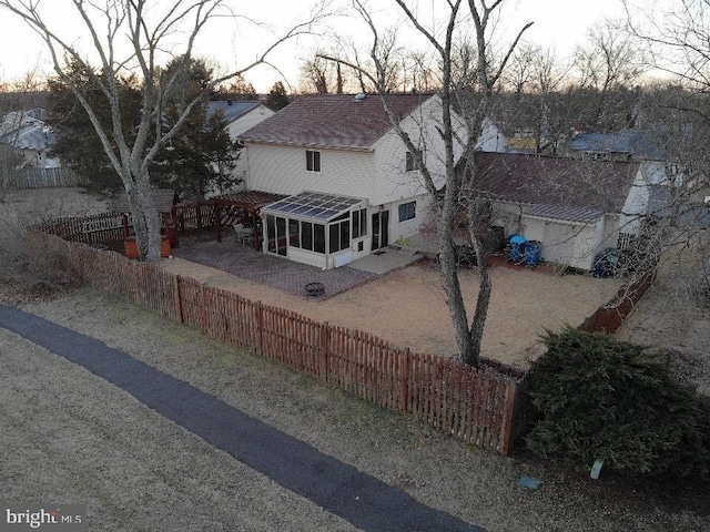 view of front of house with a patio, a shingled roof, a fenced backyard, and a sunroom