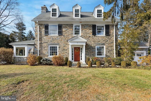 view of front of home featuring stone siding, a chimney, and a front yard