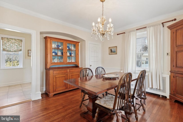 dining room with dark wood-type flooring, a wainscoted wall, and crown molding