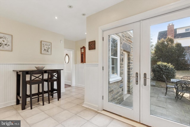 doorway with a wainscoted wall, french doors, light tile patterned floors, and recessed lighting