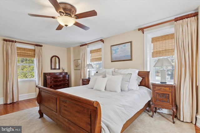 bedroom with a ceiling fan, light wood-type flooring, and baseboards