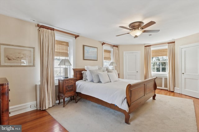 bedroom with ceiling fan, light wood-style flooring, and baseboards