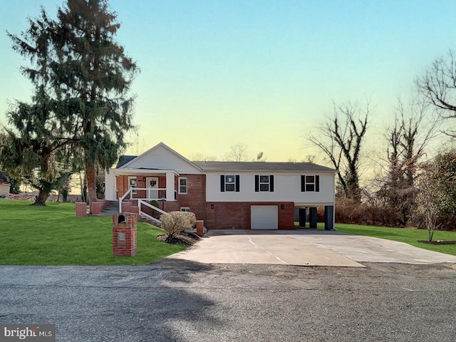 view of front of house with brick siding, a lawn, driveway, and a garage