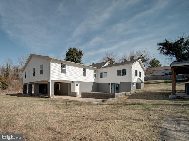 rear view of property featuring a carport, a patio area, and a lawn