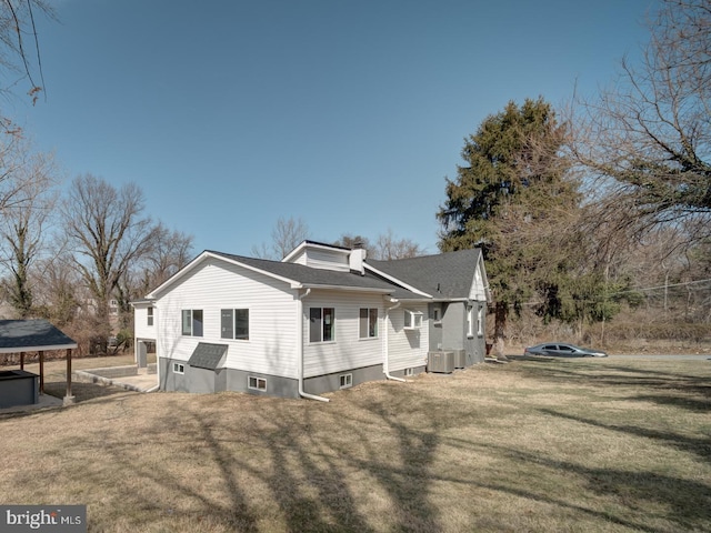 exterior space featuring central air condition unit, a chimney, and a yard