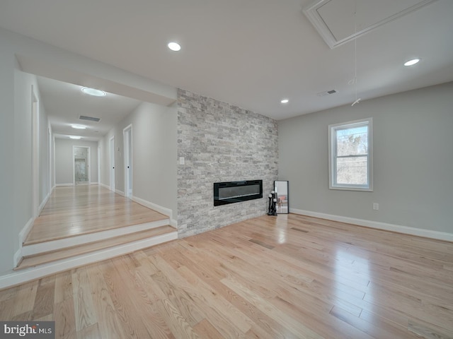 unfurnished living room with visible vents, attic access, and wood finished floors