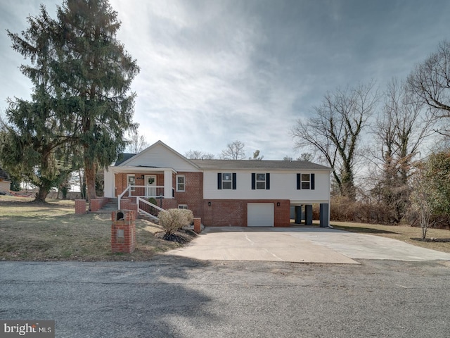 view of front of house featuring brick siding, concrete driveway, a front yard, covered porch, and a garage