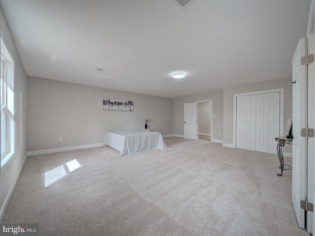 unfurnished bedroom featuring light carpet, a closet, and baseboards