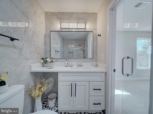 full bath featuring visible vents, toilet, vanity, a stall shower, and tile walls