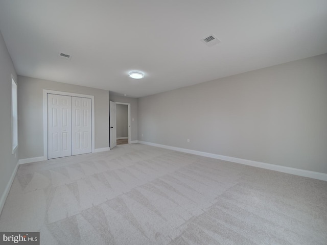 unfurnished bedroom featuring baseboards, visible vents, a closet, and light carpet