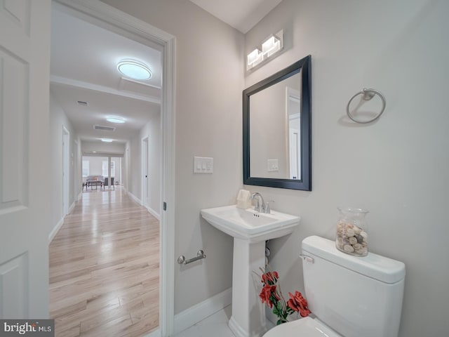 bathroom with wood finished floors, toilet, baseboards, and visible vents