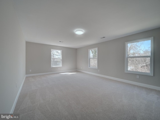 empty room featuring visible vents, baseboards, and light carpet