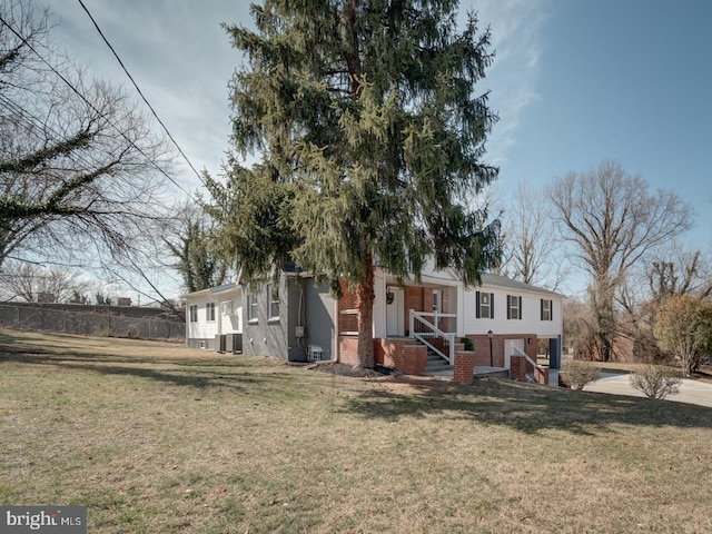 view of front of home with brick siding, central AC unit, and a front yard