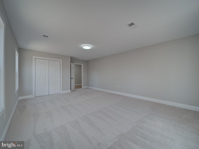 unfurnished bedroom with light colored carpet, baseboards, visible vents, and a closet