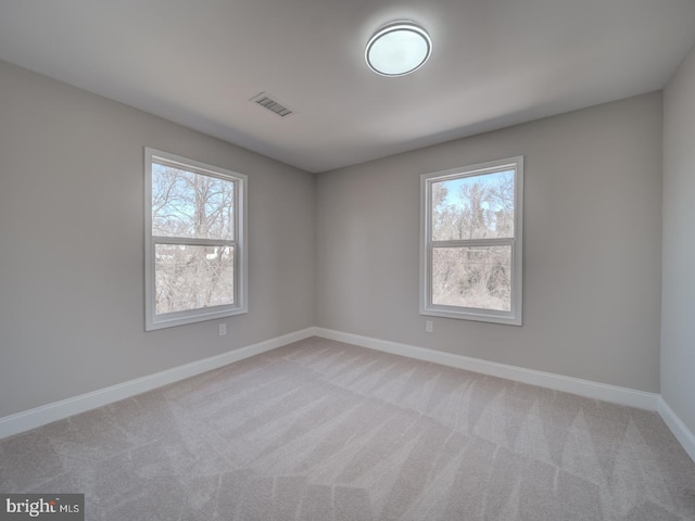 unfurnished room featuring visible vents, light carpet, plenty of natural light, and baseboards