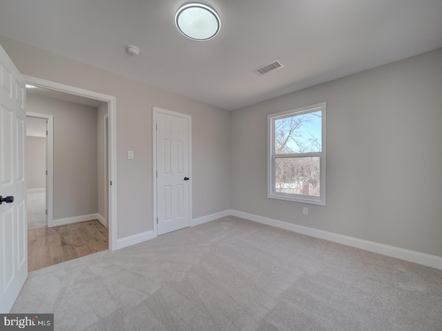 unfurnished bedroom featuring visible vents, carpet floors, and baseboards