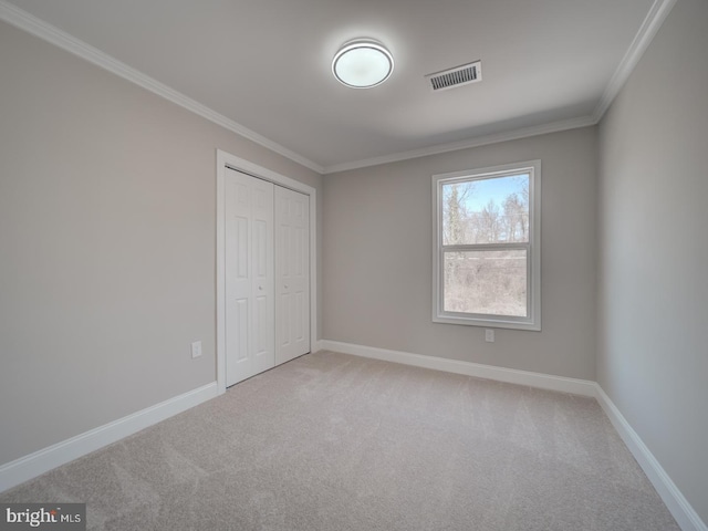 unfurnished bedroom featuring visible vents, crown molding, carpet, baseboards, and a closet