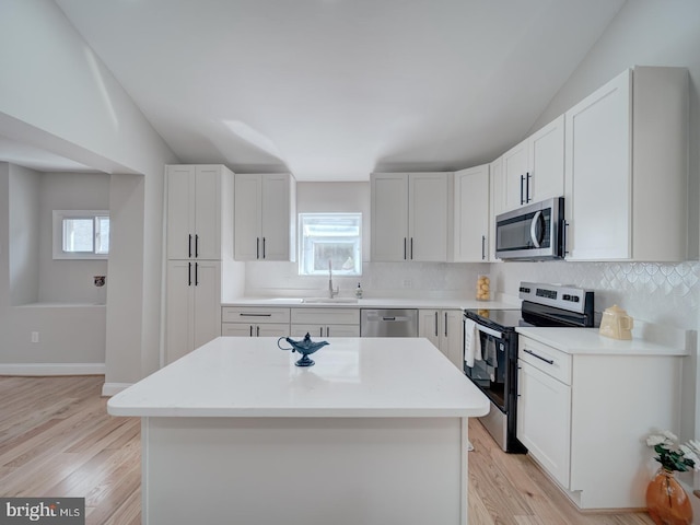 kitchen with a sink, light wood-type flooring, appliances with stainless steel finishes, and a wealth of natural light