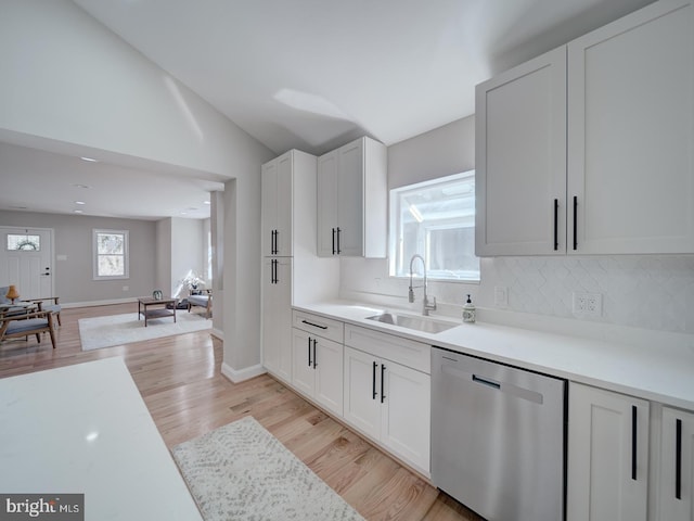 kitchen with stainless steel dishwasher, a healthy amount of sunlight, light wood finished floors, and a sink