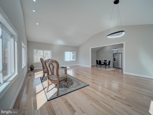 living area featuring vaulted ceiling, wood finished floors, and baseboards