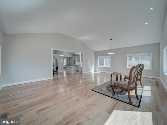 interior space featuring visible vents, baseboards, light wood-style flooring, and vaulted ceiling