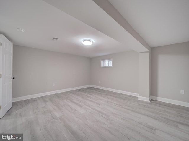 basement featuring light wood-style flooring, visible vents, and baseboards