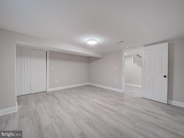 finished basement with stairs, baseboards, visible vents, and light wood-type flooring