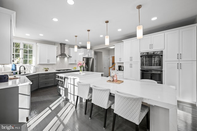 kitchen with multiple ovens, a center island, stainless steel fridge, wall chimney exhaust hood, and decorative backsplash