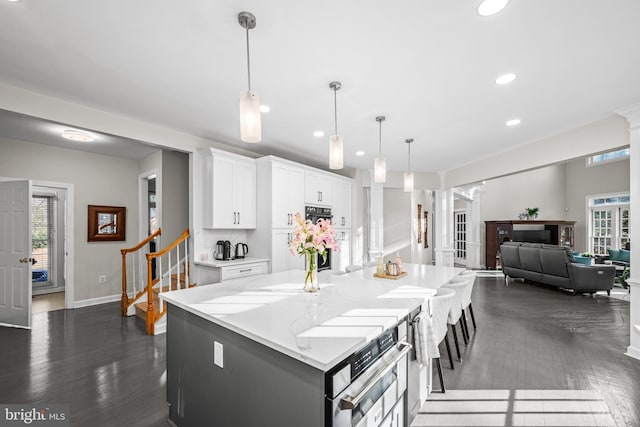 kitchen with a spacious island, light stone countertops, recessed lighting, white cabinets, and dark wood-style flooring