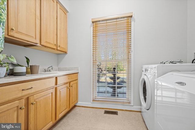 washroom with visible vents, baseboards, cabinet space, independent washer and dryer, and a sink